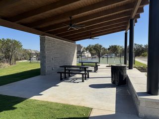 A covered picnic area with tables and fans in Parkside On The River by Perry Homes (Georgetown, TX).