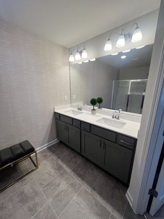 A modern bathroom featuring a double sink vanity, elegant lighting, and sleek stone tiles for a chic, contemporary feel.