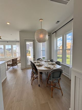 A bright, airy dining space with elegant furnishings and plenty of natural light from large windows and glass doors.