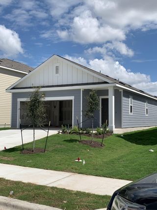 A charming gray home with white accents and landscaped yard in Hymeadow by Starlight Homes (Maxwell, TX).