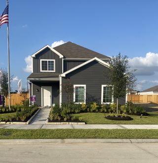 Street view A charming gray home with a manicured lawn in Wayside Village by Legend Homes (Houston, TX).