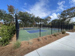 A well-maintained tennis court surrounded by lush landscaping in Sea Island Preserve by Pulte Homes (Johns Island, SC).
