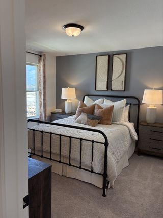 A cozy bedroom featuring a wrought iron bed, plush pillows, warm lighting, and tasteful wall art.