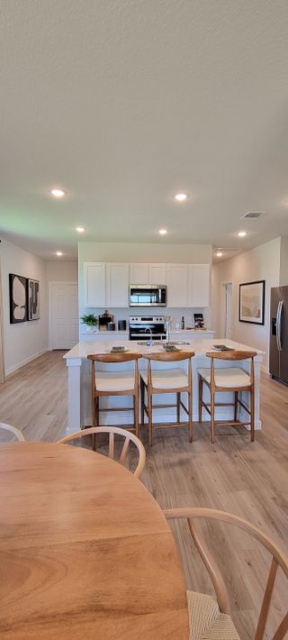 A modern kitchen featuring sleek white cabinetry, stainless steel appliances, and a spacious island with bar seating.