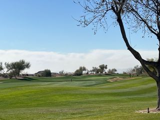 Lush green golf course with tree-dotted landscape in Club Village at Superstition Mountain by Bellago Homes (Gold Canyon, AZ).