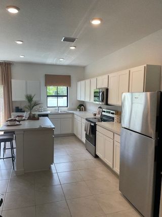 Model Home A sleek kitchen with stainless steel appliances, white cabinetry, and a central island with seating and stylish decor.