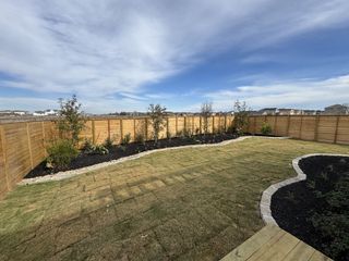 A beautifully landscaped yard with new plants and wooden fencing in Solms Landing 45' by Perry Homes (New Braunfels, TX).