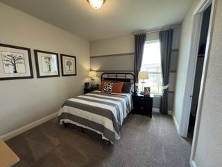 A cozy bedroom with a striped bedspread, modern wall art, and a window with gray curtains, creating a serene atmosphere.