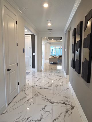 Model Home A sleek entry hallway with stunning marble-look floors and modern wall décor leading to an open-concept living space.