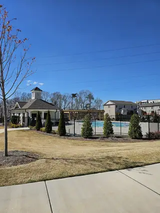 A scenic community pool area with a clubhouse and manicured lawns in Brackley Single Family by The Providence Group (Cumming, GA).