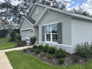 A charming gray home with white accents and lush landscaping in Marion County Spot Lots by D.R. Horton (Ocala, FL).