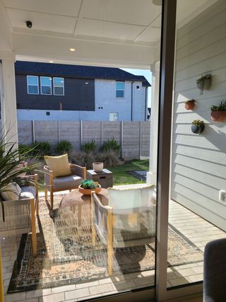 A cozy patio with wicker chairs, a patterned rug, and lush plants, perfect for relaxing and enjoying a sunny afternoon.