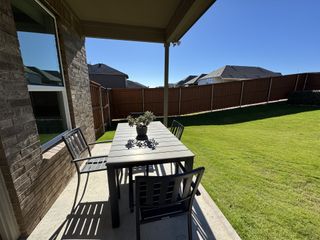Model Home A serene patio with a sleek dining set overlooking a lush, fenced backyard. Ideal for outdoor relaxation and gatherings.
