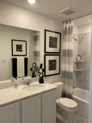 A modern bathroom featuring abstract art, sleek fixtures, and a marble-tiled shower, creating a stylish and calming space.