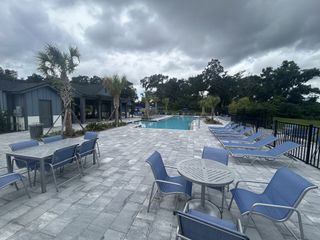A beautiful community pool area with lounge chairs in Oakfield at Mount Dora Cottage Series by David Weekley Homes (Mount Dora, FL).