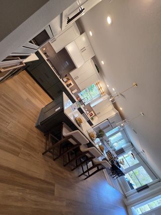 A spacious kitchen with white cabinetry, a contrasting dark island, and sleek gold pendant lights adding a modern touch.