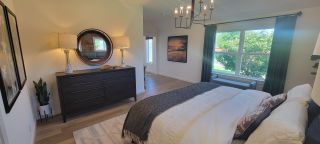 A cozy bedroom featuring stylish decor, large windows, and a modern light fixture for a relaxing ambiance.