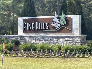 A welcoming entrance sign with landscaped greenery at Pine Hills at Cane Bay by D.R. Horton in Summerville, SC.