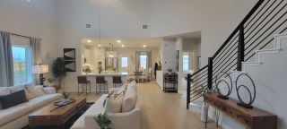 A spacious, modern living area with open layout, stylish kitchen, and sleek staircase, perfect for entertaining.
