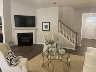 A cozy living room with a sleek TV above a fireplace, elegant seating, and a stylish glass coffee table.