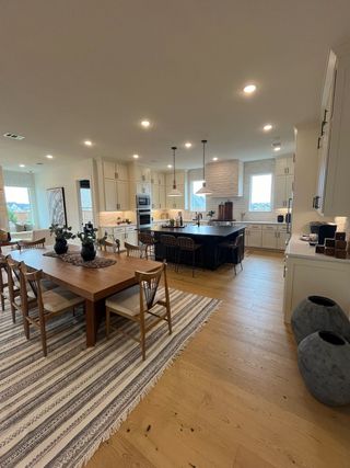 An elegant kitchen and dining area featuring a wooden table, striped rug, and modern cabinetry with ample natural light.