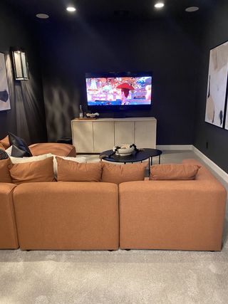 Model Home A cozy media room with plush seating, modern art, and a sleek TV setup, perfect for movie nights.