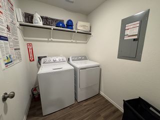 A practical laundry room with a washer, dryer, shelving for storage, and essential utilities.