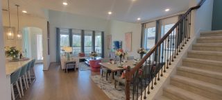 Model Home A bright, open-concept living space with hardwood floors, a dining area, and a staircase, showcasing a seamless flow throughout the home.