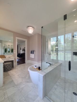 Model Home Luxurious bathroom featuring a freestanding tub, glass shower, marble tile, and elegant chandelier lighting.