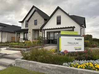 Street view A modern home with sleek stone accents and lush landscaping in Trillium 40′ by Tri Pointe Homes (Richmond, TX).