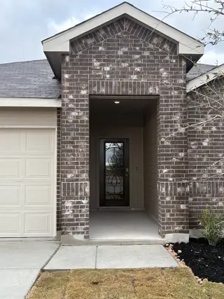 A charming brick entryway with an elegant glass door in Riverstone at Westpointe by D.R. Horton (San Antonio, TX).