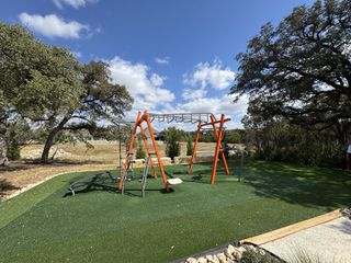 A fun outdoor fitness station with monkey bars and exercise equipment in Wolf Ranch by Coventry Homes (Georgetown, TX), set against a backdrop of greenery.