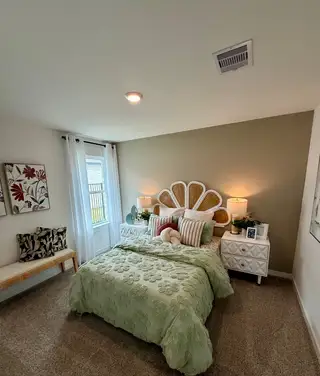 A cozy bedroom with a floral comforter, unique headboard, and elegant decor, creating a serene and welcoming atmosphere.