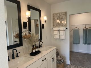 Model Home A chic bathroom featuring dual sinks, black accents, and modern décor with a cozy adjoining closet space.
