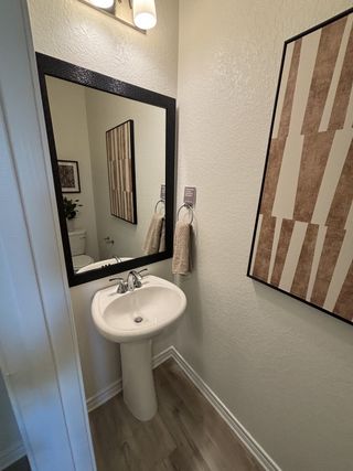 A cozy powder room featuring a pedestal sink, elegant lighting, and contemporary wall art.