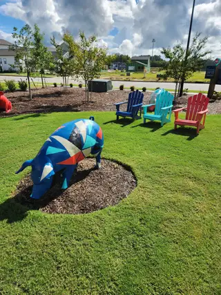 Colorful art installation with vibrant chairs in a landscaped area at Wendell Falls by Garman Homes (Wendell, NC).