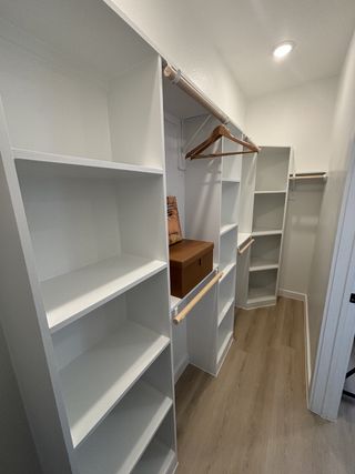Model Home A spacious walk-in closet with sleek white shelving, ample hanging space, and minimalist lighting.