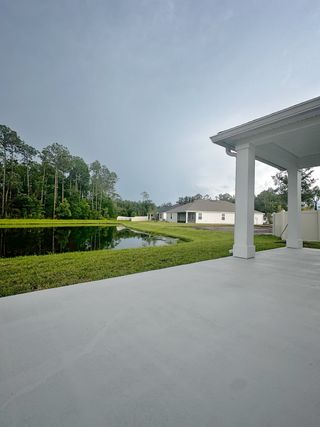 A serene backyard patio with a pond view and lush greenery in Anabelle Island - Executive Series by KB Home (Green Cove Springs, FL).