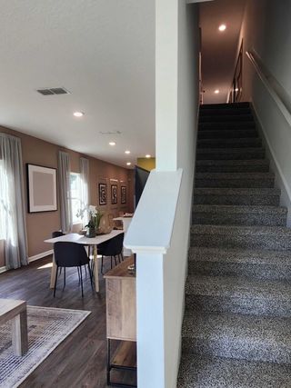 Model Home A modern interior featuring an open dining area with hardwood floors and a cozy carpeted staircase.