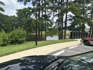 Street view A serene lakeside view with lush trees and mailboxes in Cornwallis Landing by Mungo Homes (Garner, NC).
