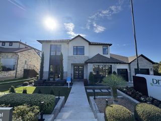 Street view A modern two-story home with a stone and stucco facade, featuring clean lines and manicured landscaping in Provence by Drees Custom Homes, Austin, TX.