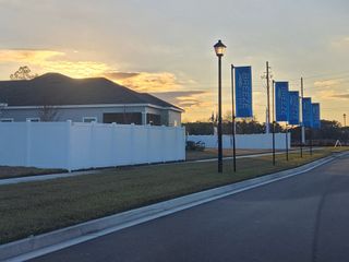 A serene street view at sunset in Saddle Oaks by Breeze Homes, featuring modern homes and tidy lawns (Jacksonville, FL).