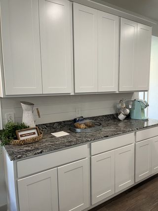 A modern kitchen with sleek white cabinets, granite countertops, and a cozy coffee corner for a stylish touch.