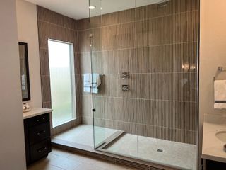 Model Home A modern bathroom with a spacious glass shower, textured tiles, and elegant vanities creating a sleek, serene ambiance.