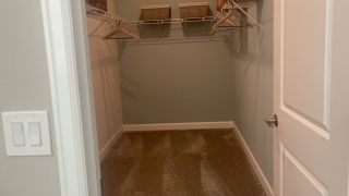 A spacious walk-in closet with sleek wire shelving, elegant hangers, and cozy carpet flooring.