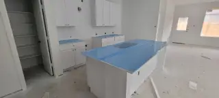 A kitchen in progress featuring white cabinetry, a large island, and protective blue covering over countertops.