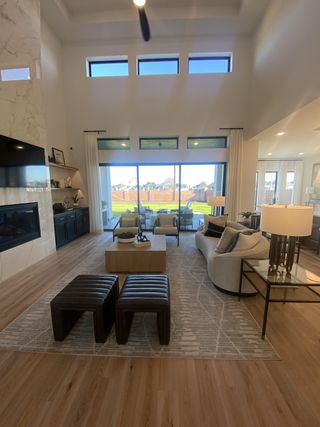 Model Home A grand living room with soaring ceilings, large windows, and a cozy fireplace for a bright and welcoming space.