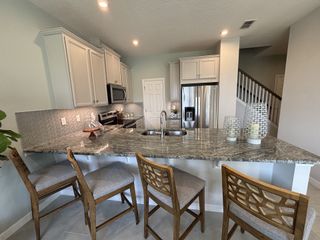 A modern kitchen with granite countertops, stainless steel appliances, and chic wooden barstools.