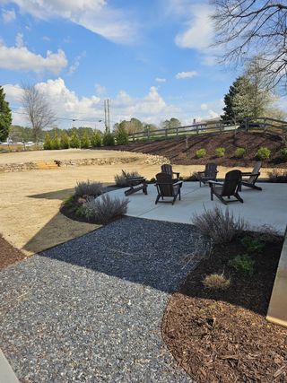 A community patio with Adirondack chairs, gravel and mulch landscaping, and lavender accents offers a relaxing outdoor space in Harmony by Kinglett Homes (Auburn, GA).