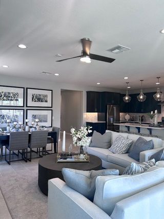 A modern living area with elegant sofas, a chic dining table, and a sleek kitchen featuring dark cabinetry and stylish lighting.